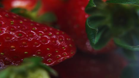 Macro-detailed-video-of-a-pile-of-strawberries,-red-strawberry,-green-leaf,-tiny-seeds,-on-a-rotating-stand,-smooth-movement