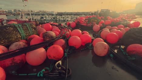 Vibrant-red-buoys-decorate-the-docks-of-a-charming-Spanish-fishing-village,-firmly-secured-along-the-coastal-pier,-providing-a-glimpse-into-the-enchantment-of-this-cozy-port-and-fishing-community