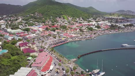 aerial-footage-of-Saint-Martin-Leeward-Islands-in-the-Caribbean-Sea,-drone-reveal-small-town-village-with-harbour-and-mountain-sea-view