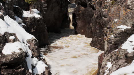 Sunlight-bathes-a-rocky-canyon,-melting-snow-and-transforming-it-into-a-babbling-stream
