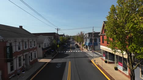 Driving-car-on-street-in-small-american-town-with-colorful-trees-during-sunny-day