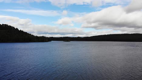 Aerial-Flying-Over-Surface-Of-Loch-an-Eilein-Surrounded-By-Pines-Of-Rothiemurchus-Forest