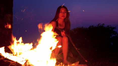asiatic-chinese-young-woman-model-girl-putting-wood-on-bonfire-while-camping-at-night