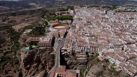aerial-circle-pan-shot-of-bullring-and-el-Tajo-gorge-bridge-in-Ronda,-Andalusia-Spain