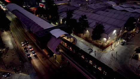 Toma-Aérea-Inclinada-De-Un-Metro,-Llegando-A-Una-Estación,-Noche-En-Santiago-De-Chile