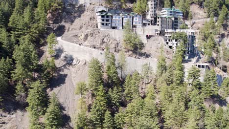 Vista-Aérea-De-Edificios-De-Varios-Niveles-Construidos-A-Lo-Largo-De-Una-Sinuosa-Carretera-De-Montaña,-Rodeados-De-Pinos.