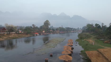 drone-shot-flying-over-the-river-towards-the-mountains-in-Vang-Vieng,-the-adventure-capital-of-Laos