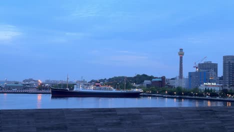 Dawn-breaks-over-a-serene-city-waterfront-with-a-large-ship-docked-and-modern-skyline-in-view