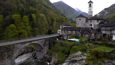Old-church-in-Lavertezzo,-Valle-Verzasca-surrounded-by-forests-and-mountains