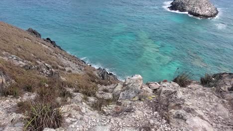 Cliff-edge-from-above,-top-of-mountain,-tilt-down-reveal-caribbean-sea-horizon,-Los-Roques