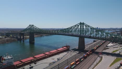 aerial-of-The-Jacques-Cartier-Bridge-crossing-the-Saint-Lawrence-River-from-Montreal-Island,-Montreal,-Quebec-during-a-sunny-day