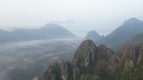 Disparo-De-Un-Dron-Volando-Sobre-Acantilados-Hacia-El-Valle-En-Vang-Vieng,-La-Capital-De-Aventuras-De-Laos