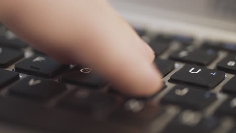 Close-up-of-a-finger-pressing-the-enter-key-on-a-laptop-keyboard,-blurred-background