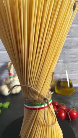 vertical-of-italian-spaghetti-pasta-Italy-flag-kitchen-tomato-garlic-basil-rope-tied-view,-kitchen-with-cooking-ingredients-close-up-spinning