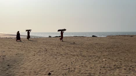 Silhouette-Einer-Armen-Migrantin,-Die-Bei-Sonnenuntergang-Am-Strand-Von-Tajpur-In-Indien-Holzscheite-Auf-Dem-Kopf-Trägt