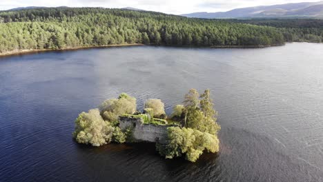 Aerial-View-Of-Ruins-Of-Loch-an-Eilein-Castle-In-Lake-Surrounded-By-Rothiemurchus-Forest