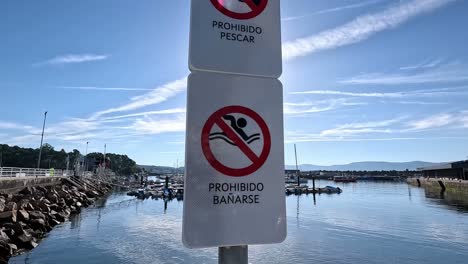 Kein-Fischfang-Und-Kein-Baden-Oder-Schwimmen-Schilder-Im-Seehafen-Befindet-Sich-Auf-Dem-Teil-Des-Wasserzugangs-Mit-Sonnenlicht-Nach-Sonnenaufgang,-Nahaufnahme-Nach-Unten-Fahren