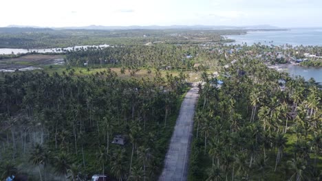 Coastal-Road-along-Fishing-Villages-in-Tropical-Siargao-Island,-Drone-View