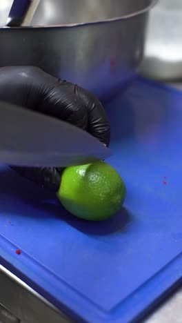 Hands-black-gloves-with-knife-slicing-cutting-lime-lemon,-close-up-slow-motion,-healthy-fruit-food-with-vitamine
