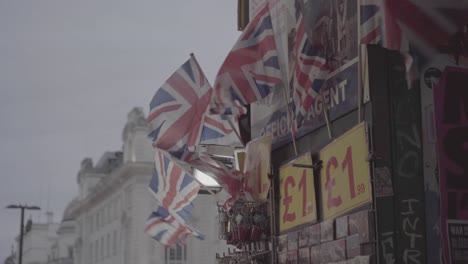 Some-small-union-jack-flags-swinged-by-the-wind-on-a-newspaper-corner-shop's-wall-in-Piccadilly-Circus