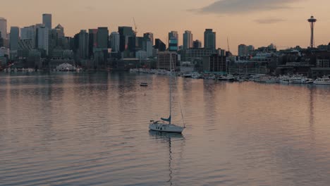 Ein-Einzelnes-Segelboot-Ruht-Während-Der-Goldenen-Stunde-Vor-Der-Uferpromenade-Und-Skyline-Von-Seattle-Auf-Dem-Ruhigen-Wasser-Des-Lake-Union