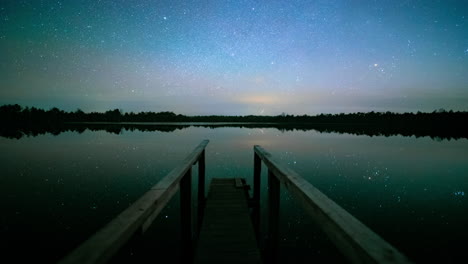 Ein-Holzsteg-Führt-Zum-See,-Der-Den-Faszinierenden-Sternenhimmel-Im-Wald-Widerspiegelt