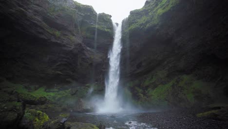 Una-Cascada-En-Islandia,-Rodeada-De-Altos-Acantilados---Cámara-Lenta