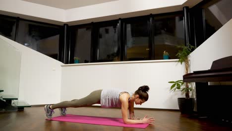 Woman-doing-plank-exercise-on-mat-at-home,-evening-indoor-workout,-health-focus