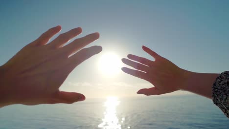 Couple's-hands-raised-toward-the-sun-on-the-horizon-sea