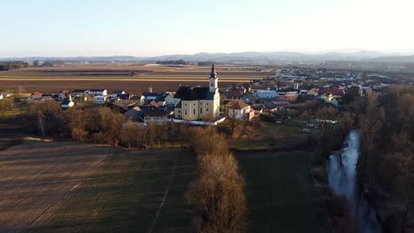 Aerial-push-toward-Church-in-small-European-farming-town-at-sunset