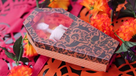 Orange-patterned-box-on-a-bed-of-vibrant-Day-of-the-Dead-flowers,-shallow-focus