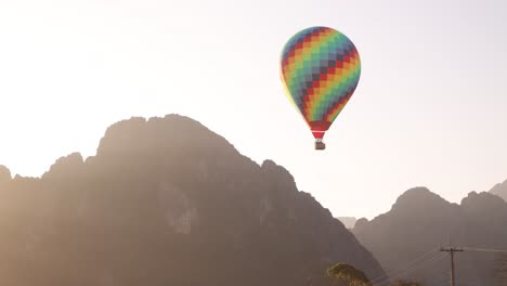 colorful-hot-air-balloon-floating-by-mountain-peaks-in-Vang-Vieng,-the-adventure-capital-of-Laos