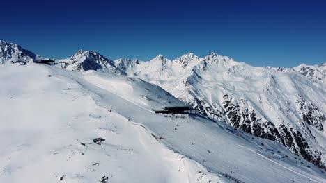 Ski-resort-in-high-Alps-with-pristine-white-snowy-slopes,-aerial