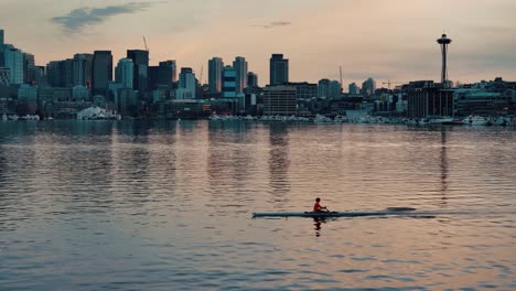 Un-Solo-Remero-En-Un-Bote-Rema-A-Través-Del-Lago-Union-En-Seattle-Con-El-Horizonte-Y-La-Aguja-Espacial-Al-Fondo