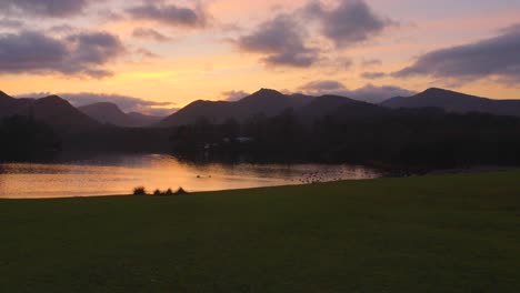 Tonos-Del-Atardecer-Sobre-Derwentwater-Con-Siluetas-De-Colinas-En-El-Distrito-De-Los-Lagos,-Inglaterra,-Aguas-Tranquilas