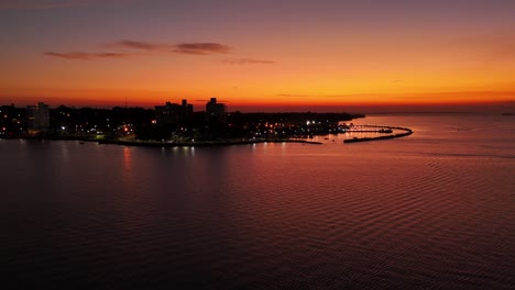 Forward-Drone-shot-of-Posadas-port-with-skyline-and-sunset,-Argentina