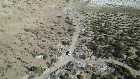 Trash-Strewn-Along-the-Roadside-Near-a-White-Vehicle-in-Mulege,-Baja-California-Sur,-Mexico---Drone-Flying-Forward