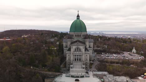 aerial-front-view-of-Saint-Joseph's-Oratory-of-Mount-Royal,-Roman-Catholic-minor-basilica-located-in-Montreal-Quebec-,-cityscape-skyline-at-distance