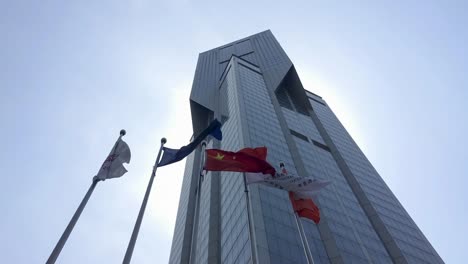 Flags-waving-in-wind-in-front-of-JW-Marriott-skyscraper-hotel-in-Shanghai,-China