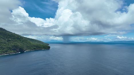 Weh-island's-northern-coast-with-distant-rain,-showcasing-the-lush-landscape-and-vast-ocean,-aerial-view