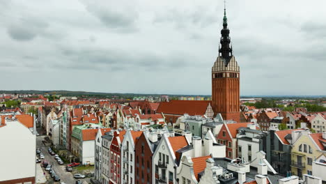 Atemberaubende-Luftaufnahme-Von-Elbląg,-Mit-Dem-Hoch-Aufragenden-Turm-Der-Kathedrale,-Der-Sich-Majestätisch-über-Die-Bezaubernde-Reihe-Von-Bunten,-Giebelförmigen-Dächern-Und-Engen-Gassen-Der-Altstadt-Erhebt---Polnisch