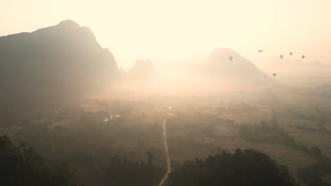 drone-shot-of-sunrise-through-mountain-valley-in-Vang-Vieng,-the-adventure-capital-of-Laos