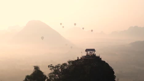 drone-shot-of-viewpoint-and-hot-air-balloons-during-sunrise-in-Vang-Vieng,-the-adventure-capital-of-Laos