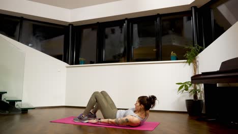 Woman-doing-heel-touches-on-yoga-mat-at-home,-evening-workout,-fitness-routine,-indoors
