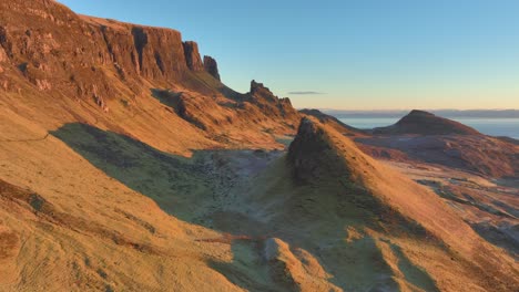 Close-flyby-of-landslip-peak-towards-cliffs-bathed-in-winter-dawn-light