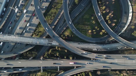 A-top-down-bird's-eye-view-of-complex,-interwoven-highway-and-interstate-on-ramps-and-off-ramps-filled-with-traffic-of-driving-cars