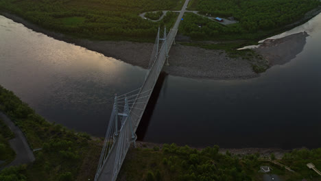 Aerial-view-backwards-over-the-Sami-Bridge-and-river,-sunset-in-Utsjoki,-Finland