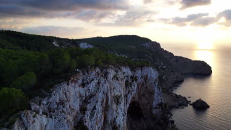 Ibiza-sunset-overlooking-a-rocky-sea-cliff-and-calm-ocean