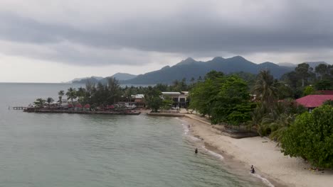 Vista-Aérea-A-Lo-Largo-De-La-Costa-De-La-Playa-De-Kai-Bae-Con-Un-Paisaje-De-Bosque-Tropical-En-El-Fondo