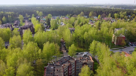 Green-town-in-Latvia-landscape-on-sunny-summer-day,-aerial-descend-view